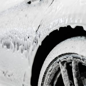 Car wash. The car thresholds is covered with white flowing foam at a carwash