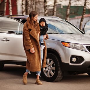 Young mother and child stand near they suv car. Safety driving concept.